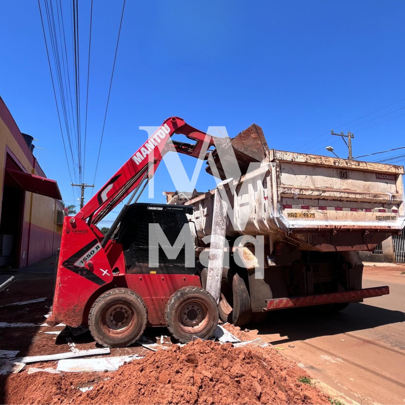 Minicarregadeira Manitou carregando entulho em caminhão caçamba