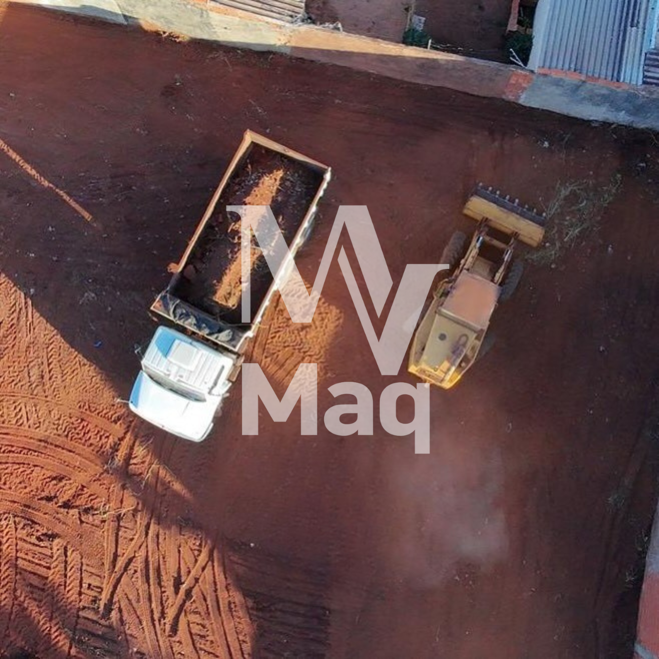Vista aérea de caminhão caçamba e pá carregadeira em terreno nivelado